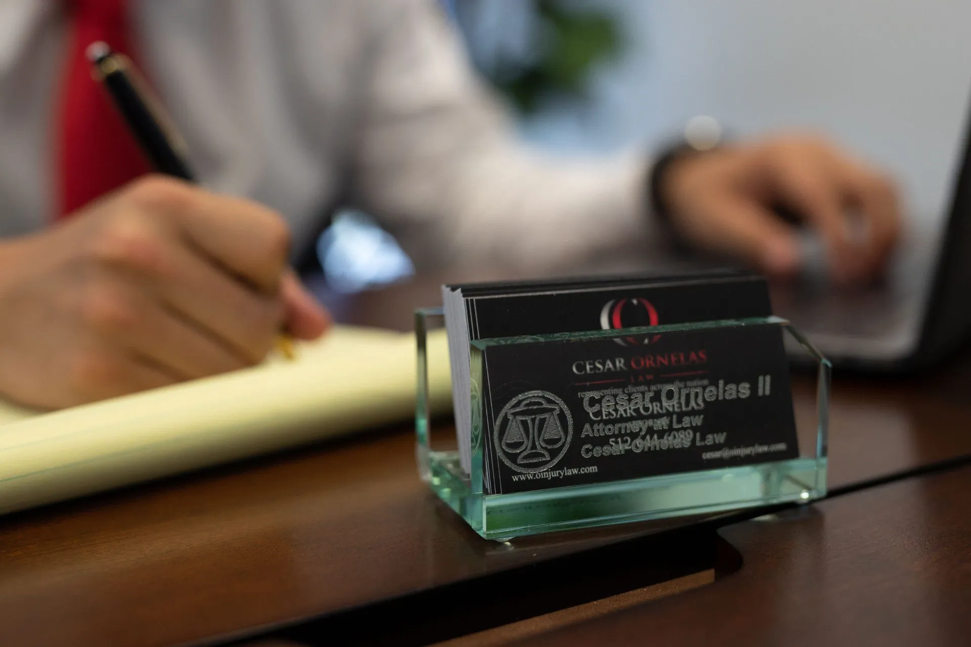 Injury Lawyer Cesar Ornelas' business cards in a card holder on a desk.