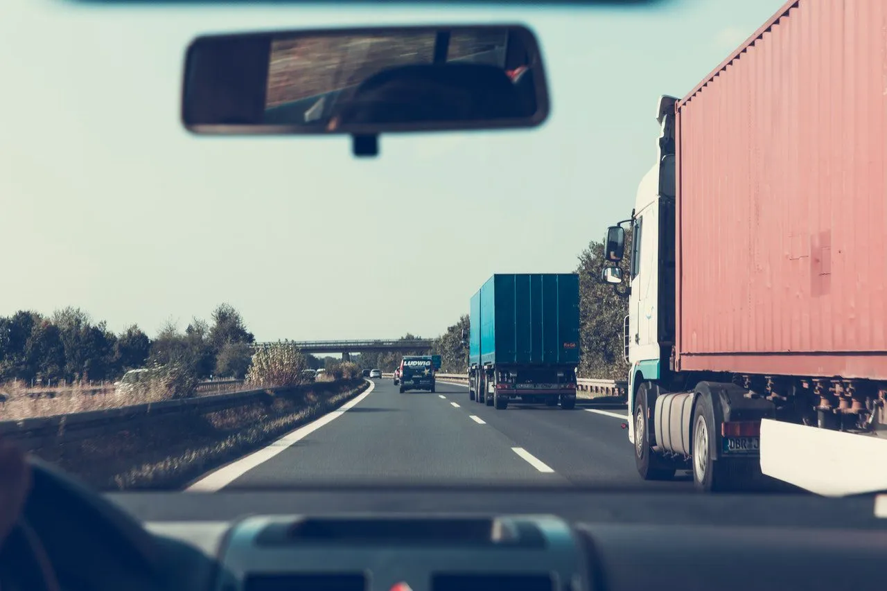Semi-trucks traveling on the right hand lane of a two-lane highway.