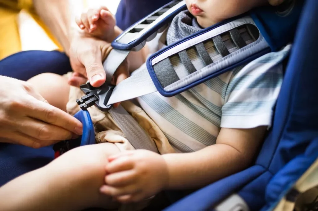 A person fastening a child into a car seat.