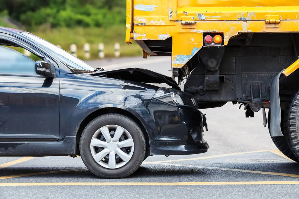 Accident on the road involving a black car and a yellow truck.
