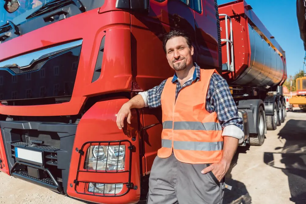 Truck driver in front of his freight forward lorry looking at camera