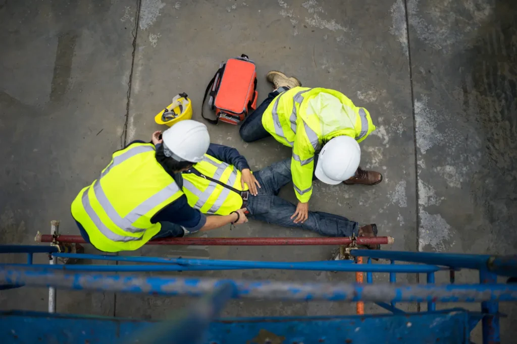 An injured construction worker on the floor with help nearby.