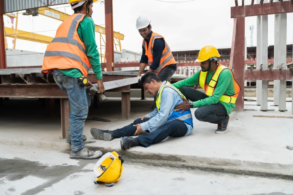 A construction worker injured and sitting on the floor.